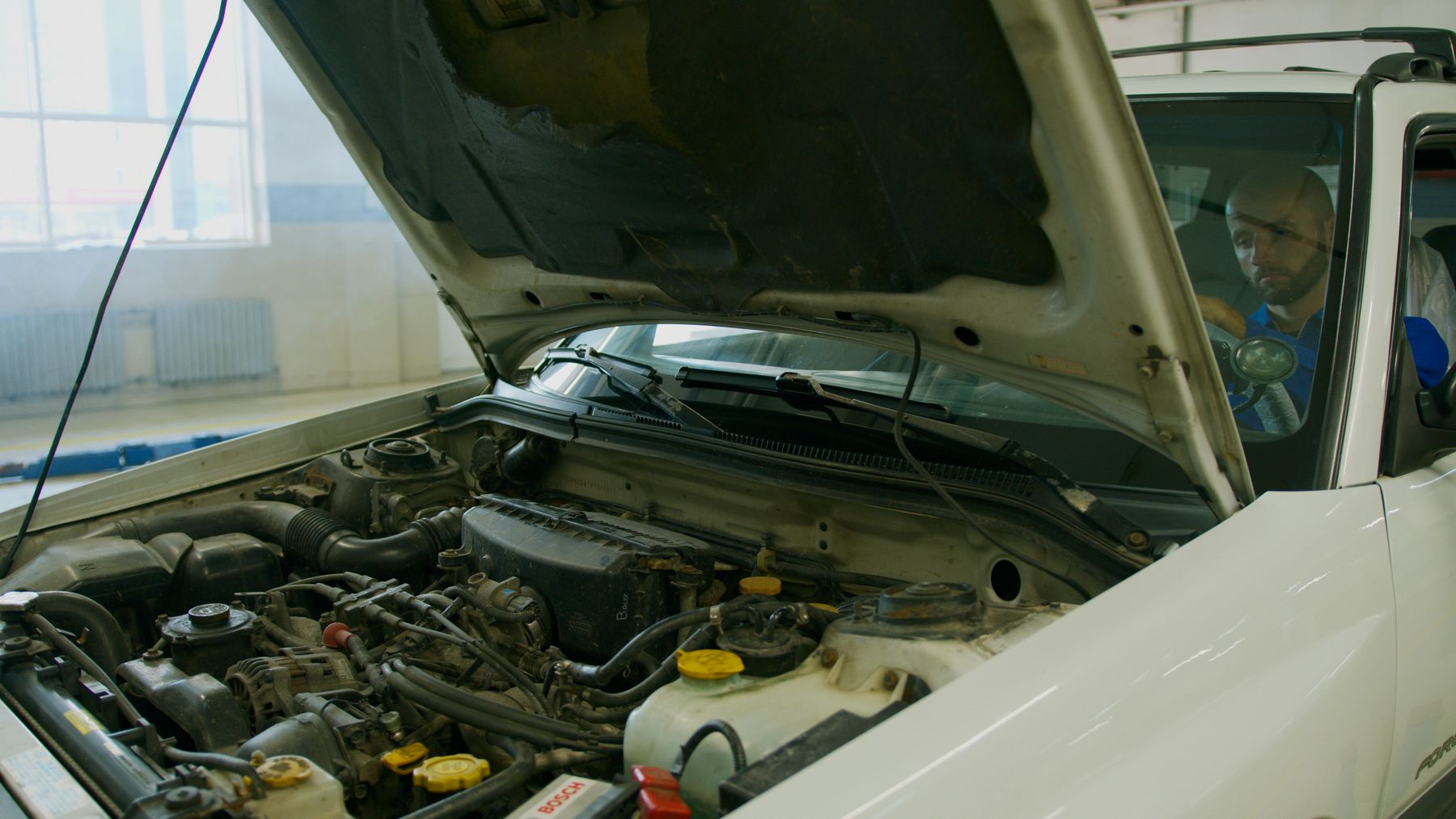 Mechanic checking an engine under an open bonnet