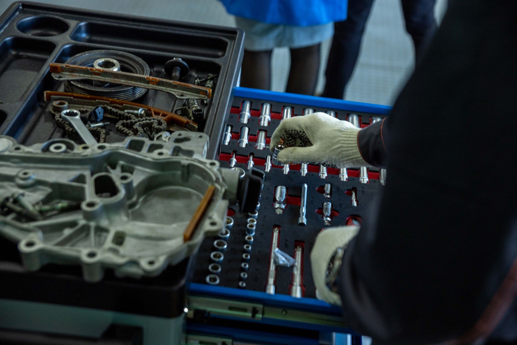 Gloved hands sorting engine parts and tools